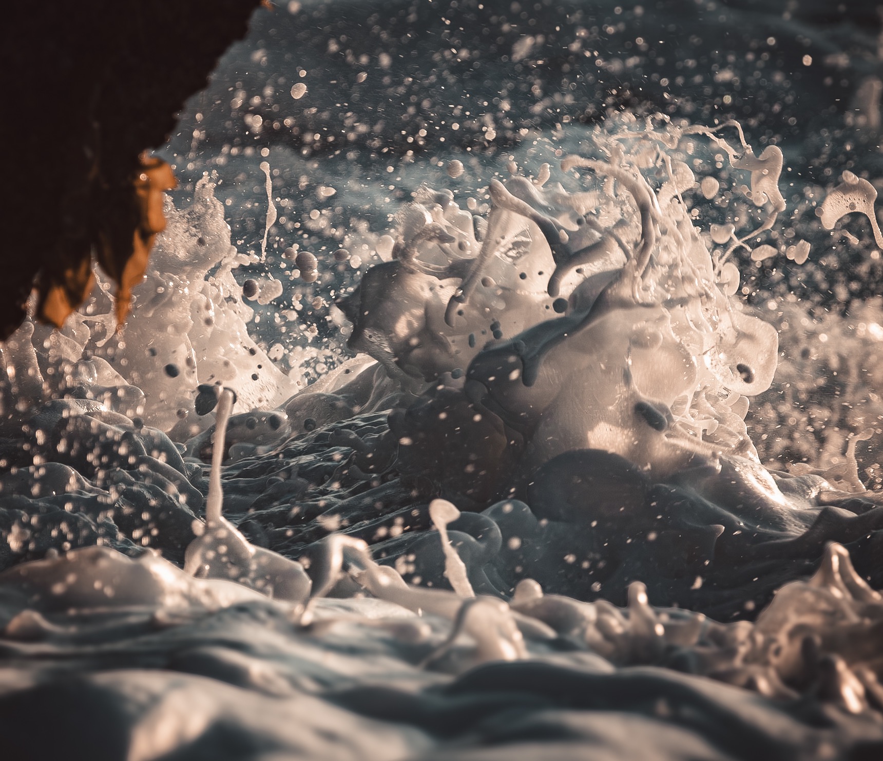 Sunlit sea foam splashing over dark water